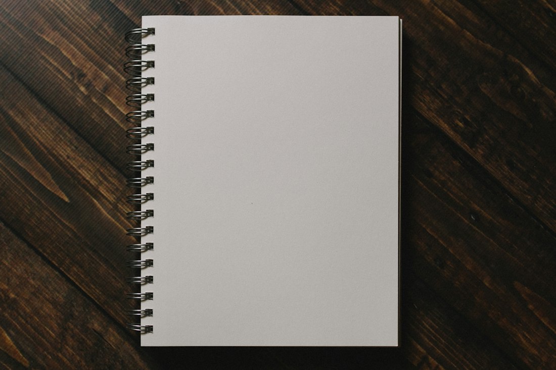 White Spiral Notebook on Wooden Table
