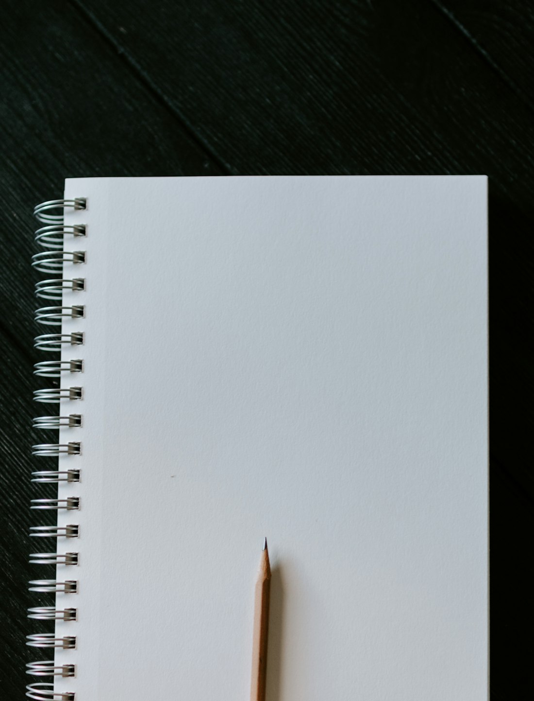 White Spiral Notebook on Black Wooden Table